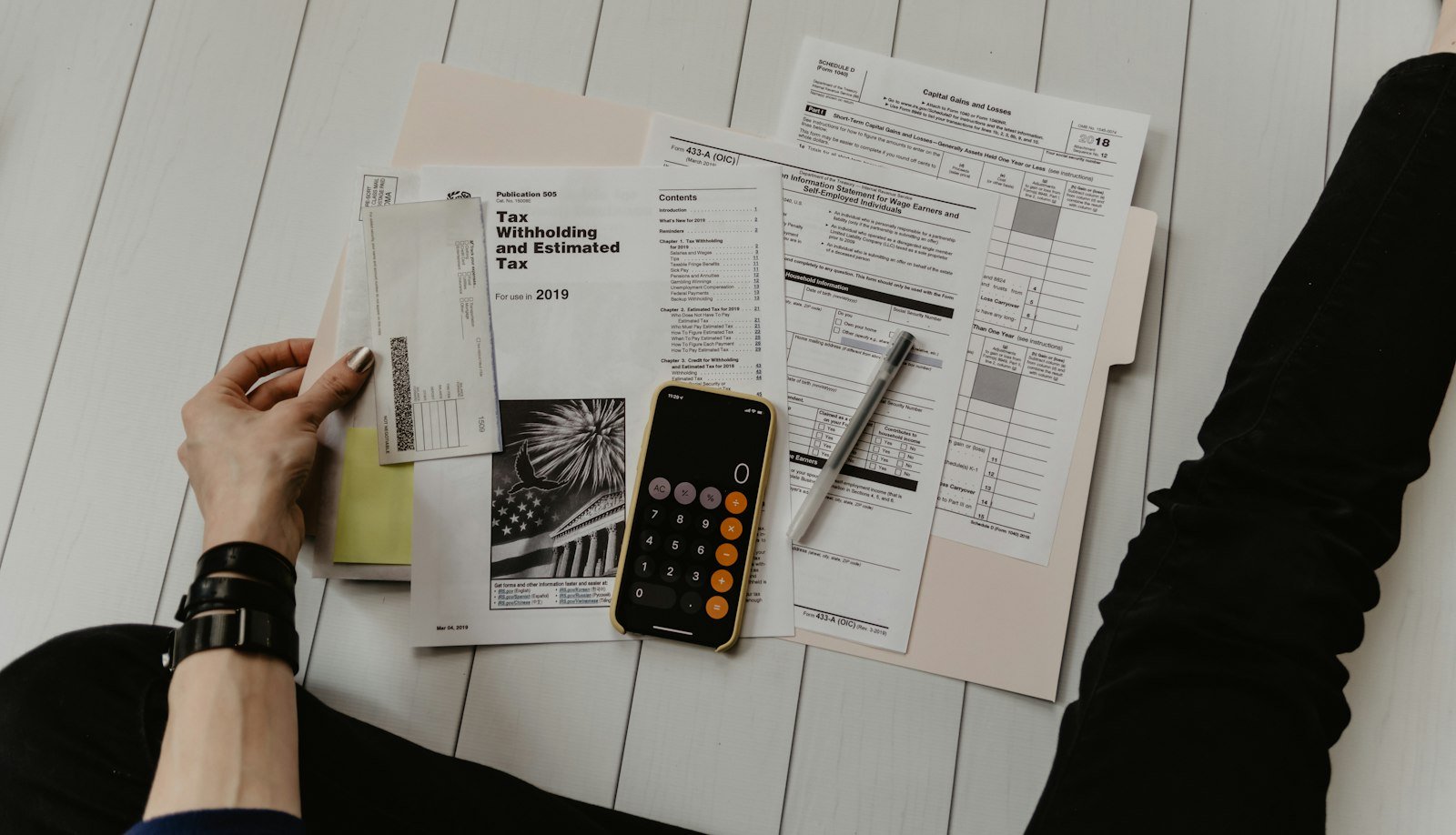Hand with pen reviewing financial charts and graphs